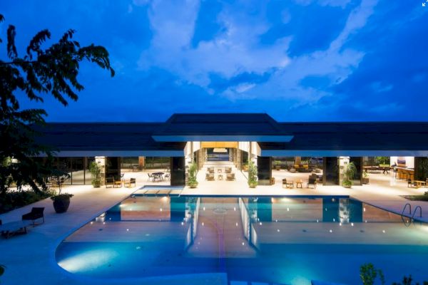 A modern building with open seating and a swimming pool, under a dramatic evening sky.