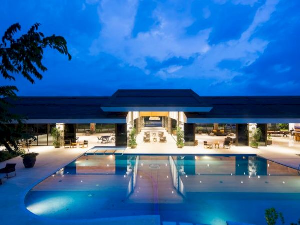 A modern building with open seating and a swimming pool, under a dramatic evening sky.