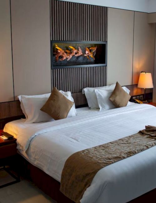A neatly arranged hotel room with a large bed, warm lighting, and elegant decor, creating a cozy and inviting atmosphere for guests.