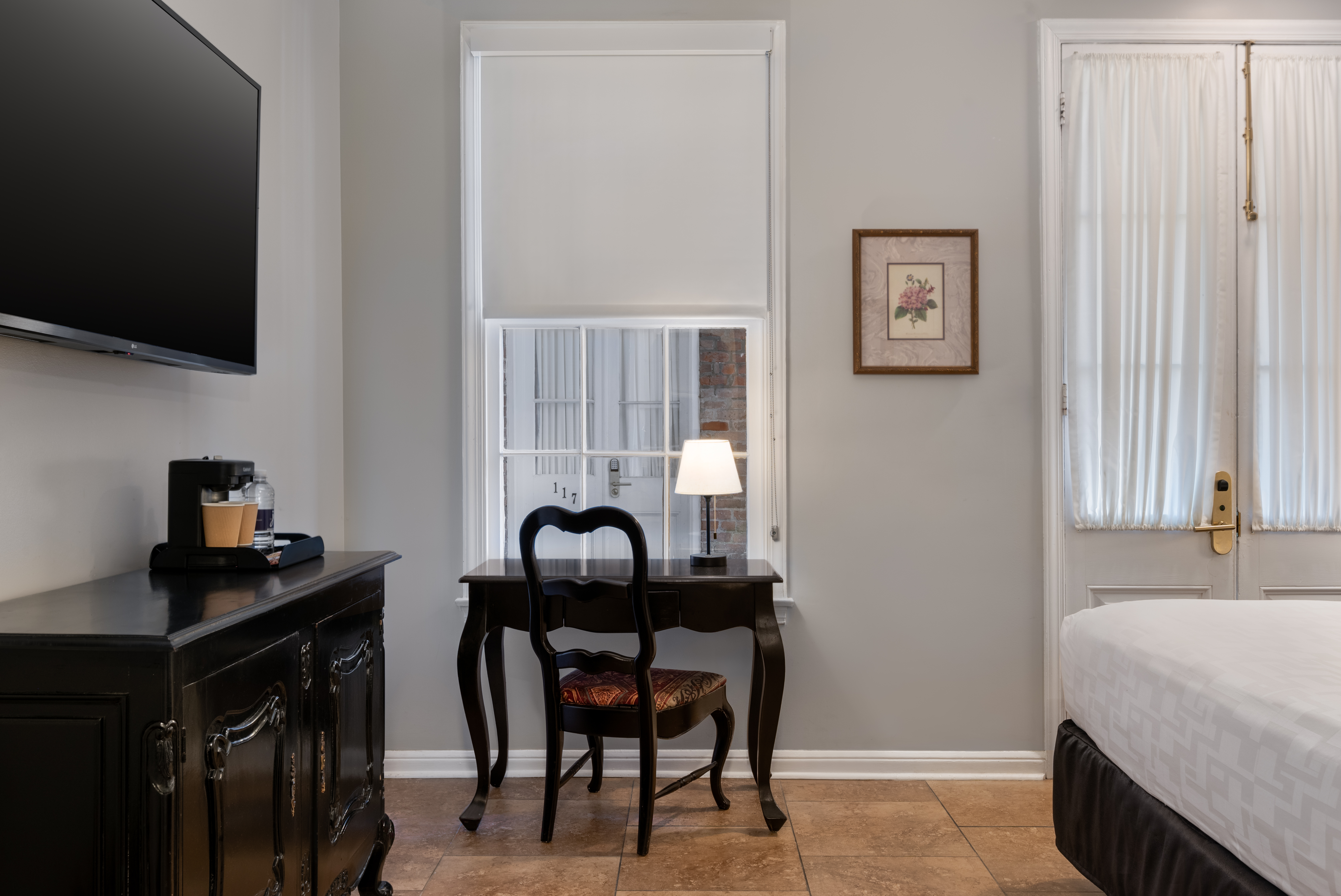 A hotel room with a desk, chair, window, and bed.