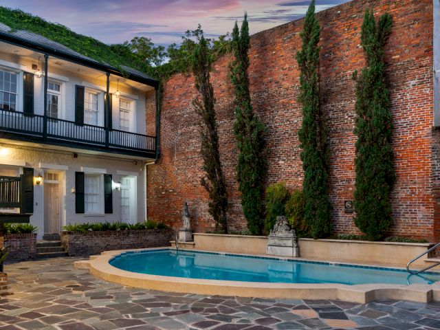A pool surrounded by a brick wall and a balcony