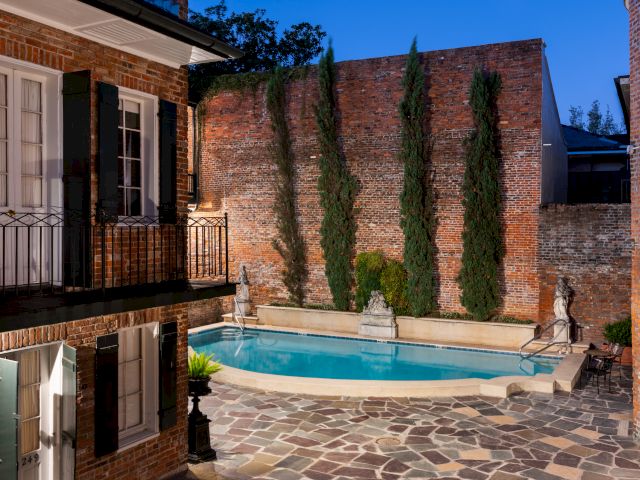 A small pool surrounded by a brick wall and a balcony.