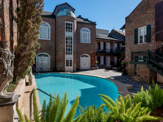 A pool surrounded by a brick building and plants