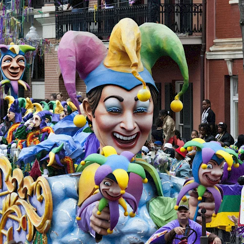 A vibrant Mardi Gras parade float featuring a jester theme, colorful costumes, and a cheerful crowd on a city street.