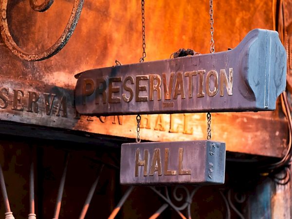 The image shows a weathered sign reading "Preservation Hall" on a rustic exterior, suggesting a historic or cultural venue.