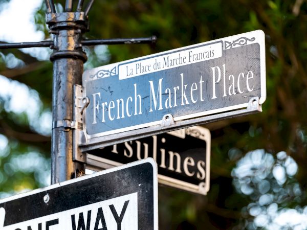 The image shows street signs for French Market Place and Ursulines, along with a one-way sign.