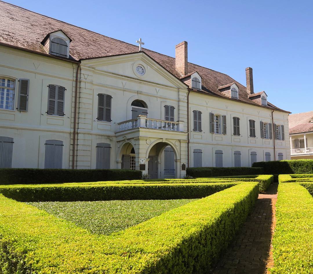 A large white building with a manicured garden in front of it.