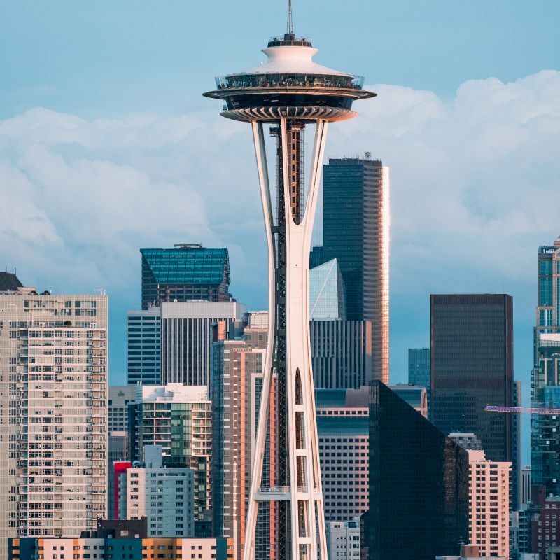 The image shows the Space Needle, a prominent observation tower, with a backdrop of skyscrapers in a cityscape.