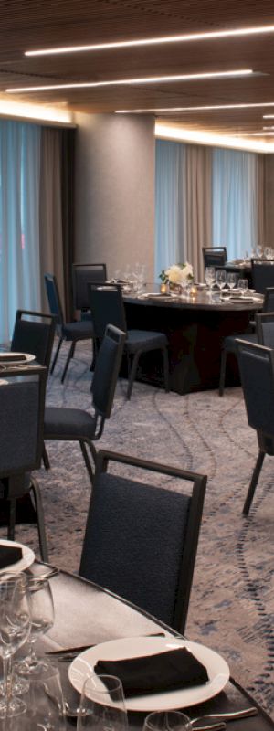 A banquet hall set up with round tables, chairs, elegant tableware, and floral centerpieces, ready for an event or gathering.