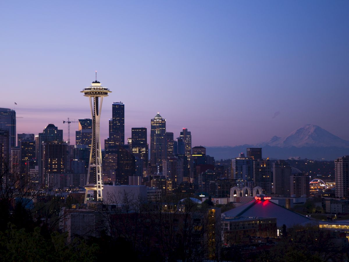 Seattle skyline at dusk with the Space Needle and Mount Rainier in the background.